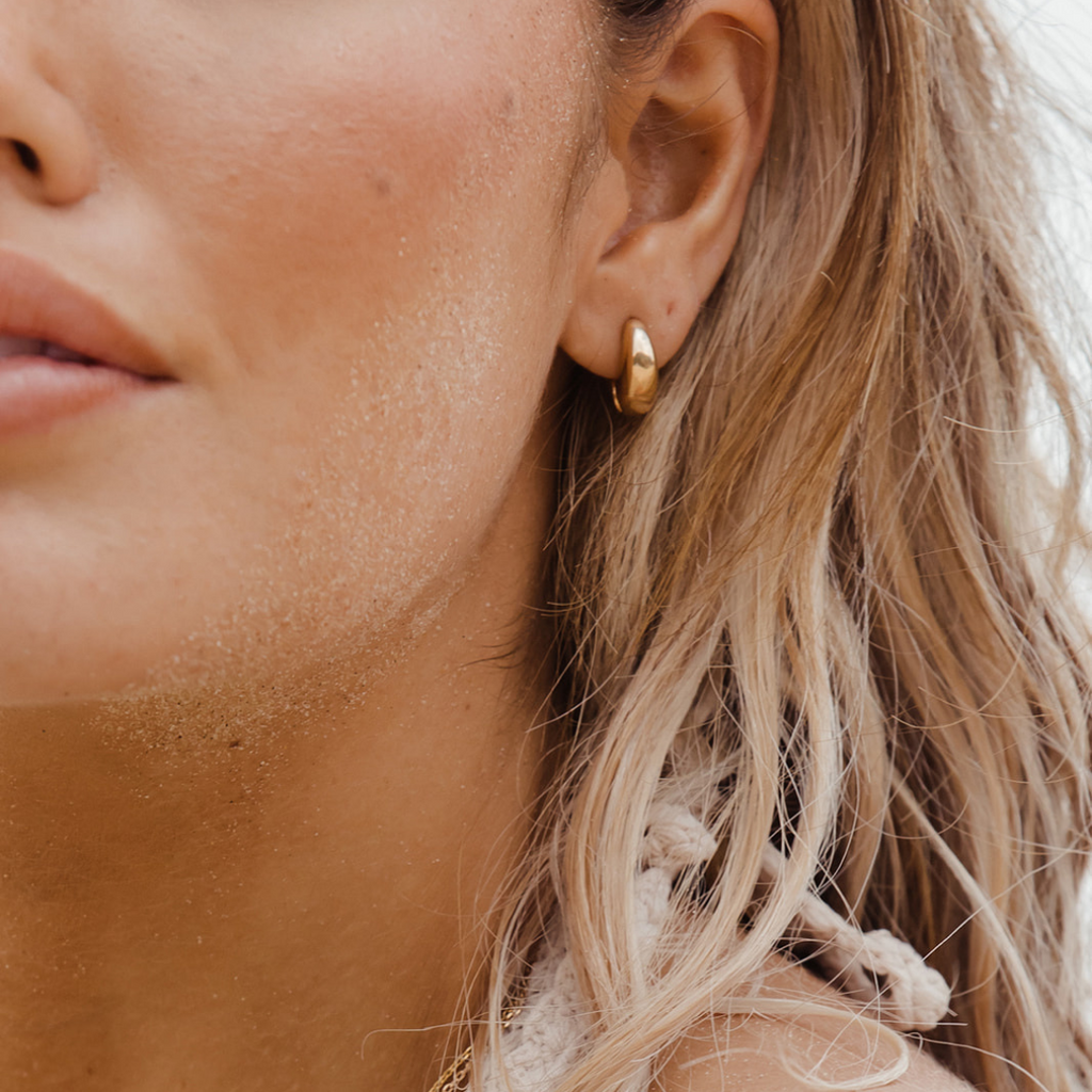 model wears a small gold huggie hoop earring