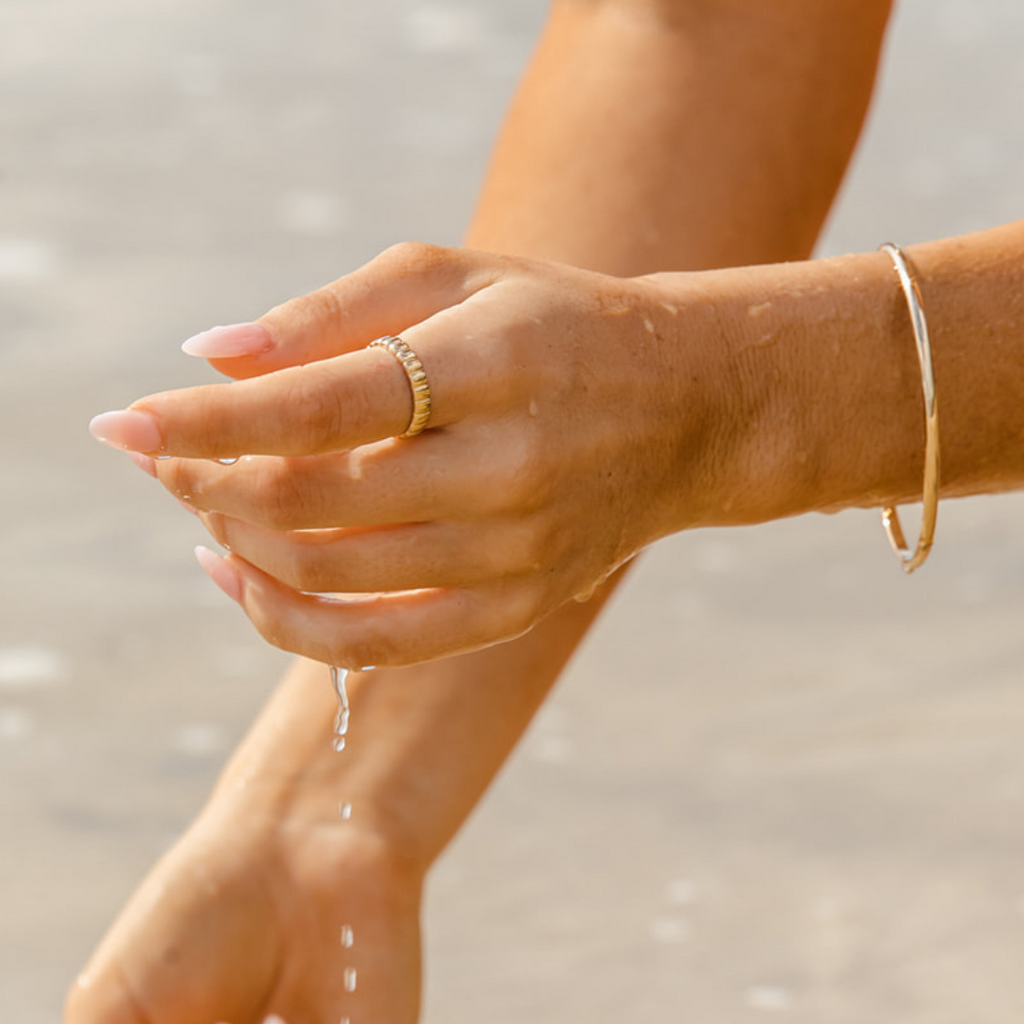 yellow gold ring and bangle worn on a womans hand